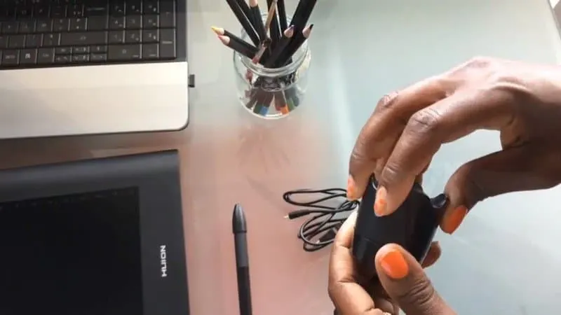 Huion graphic tablet being installed and set up showing tablet, computer, colored pencils and hands