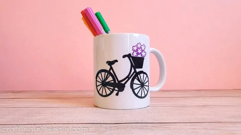 mug with black bicycle silhouette and markers in the mug