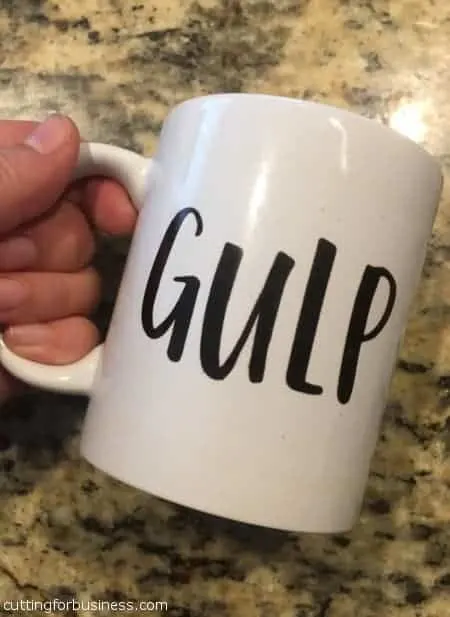 hand holding white coffee mug with word gulp