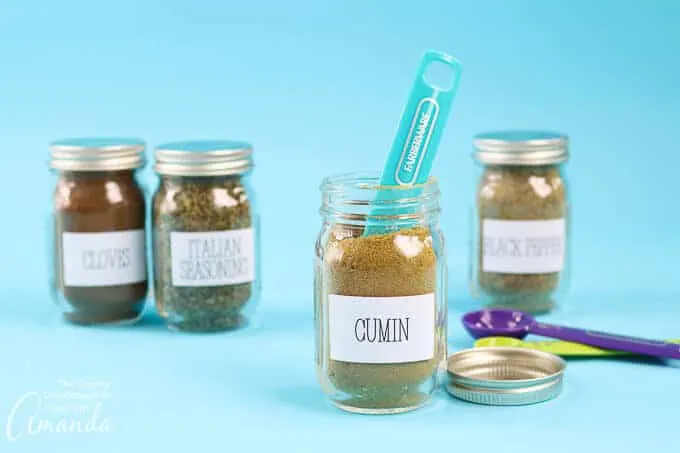 Four mason jars with white labels. Spoon sitting in the lid of one of the jars.