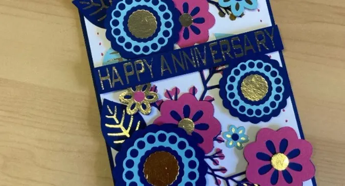 greeting card with cut out flowers and the word happy anniversary