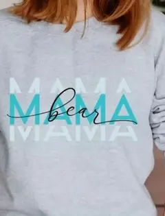 woman wearing a mother's day sweatshirt made with a mama bear font sublimation file. The sleeves of the sweatshirt have been pushed up to the elbows.