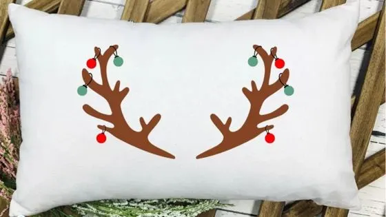 reindeer antlers draped with christmas ornament balls on a white pillowcases