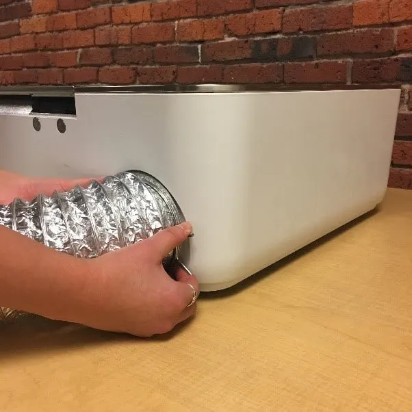 person connecting glowforge air filter to laser cutting machine