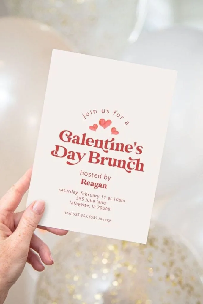 A hand holding a printable Galentine's day brunch invitation card.