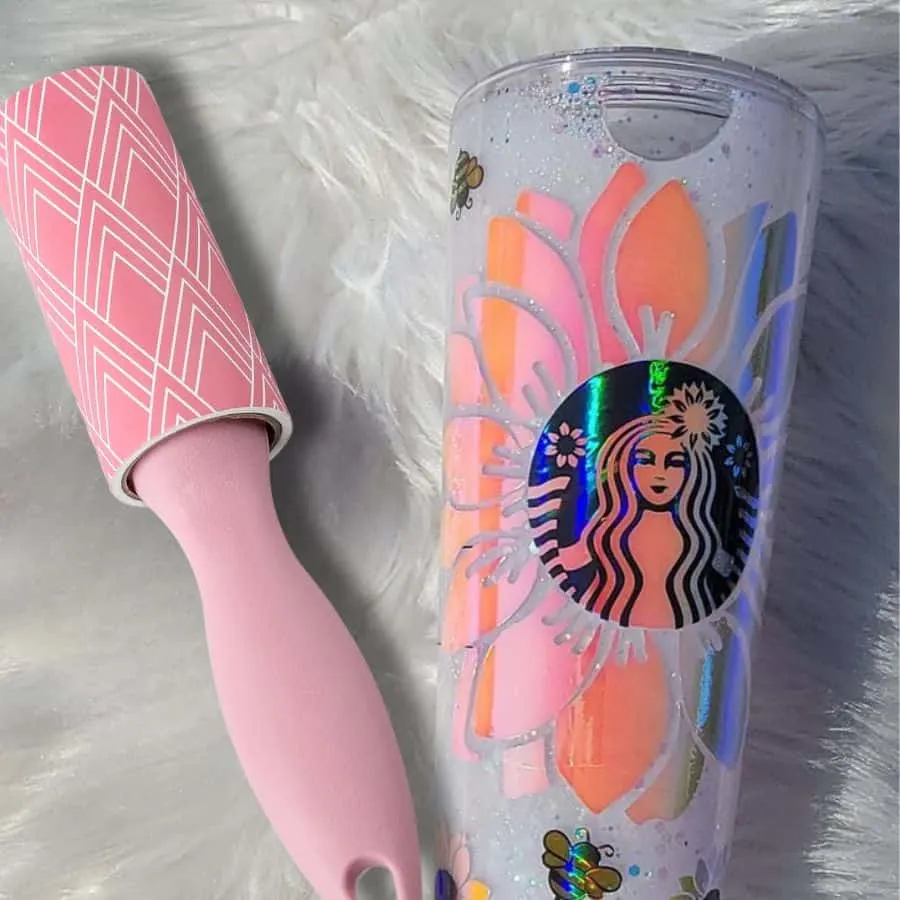 The tapered tumbler with a Starbucks holographic wrap on it and a pink lint roller next to the tumbler.