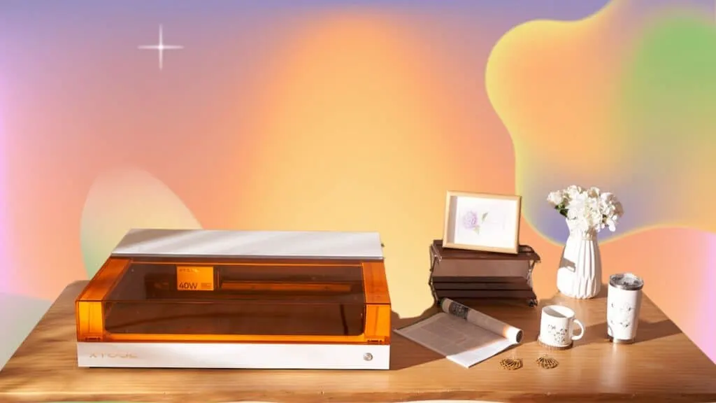 The xTool S1 white laser engraver on a wooden table with engraved crafts.