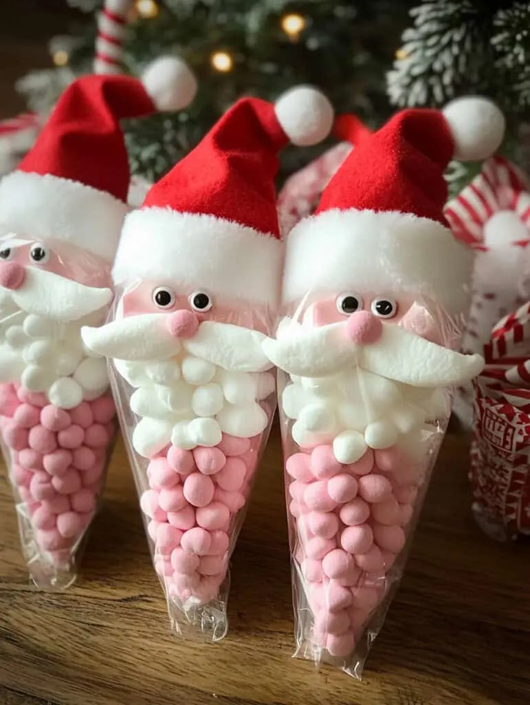 A set of adorable, Santa-themed hot cocoa gift bags, perfect for the holiday season. Each bag is a cone-shaped clear plastic treat bag filled with ingredients layered to resemble Santa&rsquo;s face.